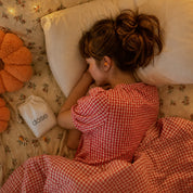 A woman resting with orange Dose Earplugs beside a dose-branded pouch